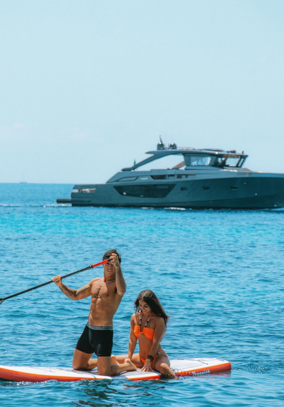 Kashi paddleboarding past a yacht